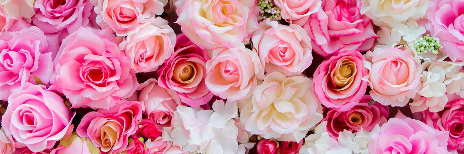 Various shades of pink and white roses closely packed together, creating a dense floral arrangement.