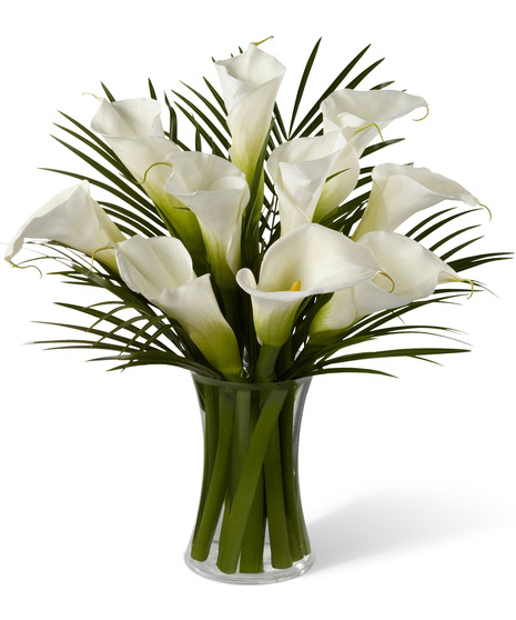 White calla lilies with special greens in a glass vase