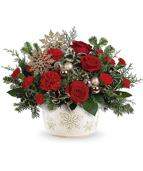 Christmas flowers arranged in a white vase with snowflakes on it.