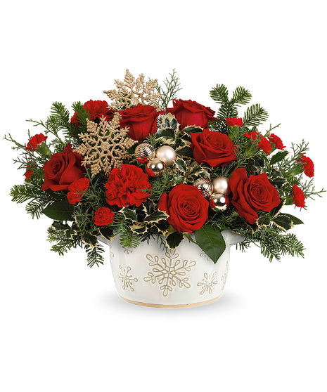 Christmas flowers arranged in a white vase with snowflakes on it.