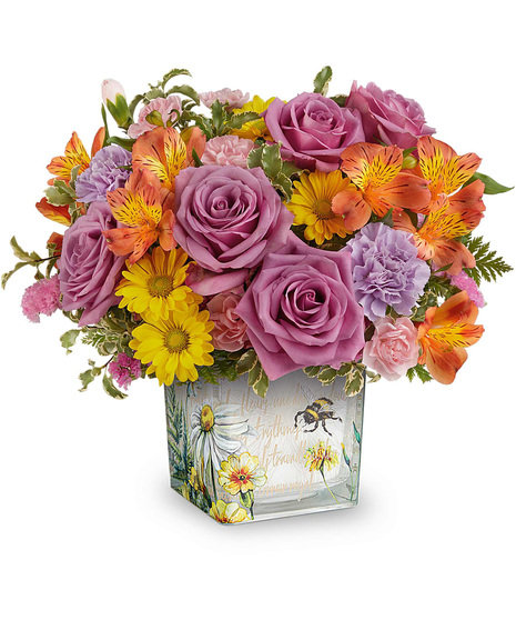 Floral Buzz Bouquet with orange alstroemeria, lavender carnations, yellow daisies, and pink blooms in a vintage inspired glass cube vase.